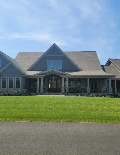 A large gray house with a large driveway.