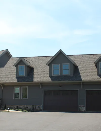 A gray house with two garages and a driveway.
