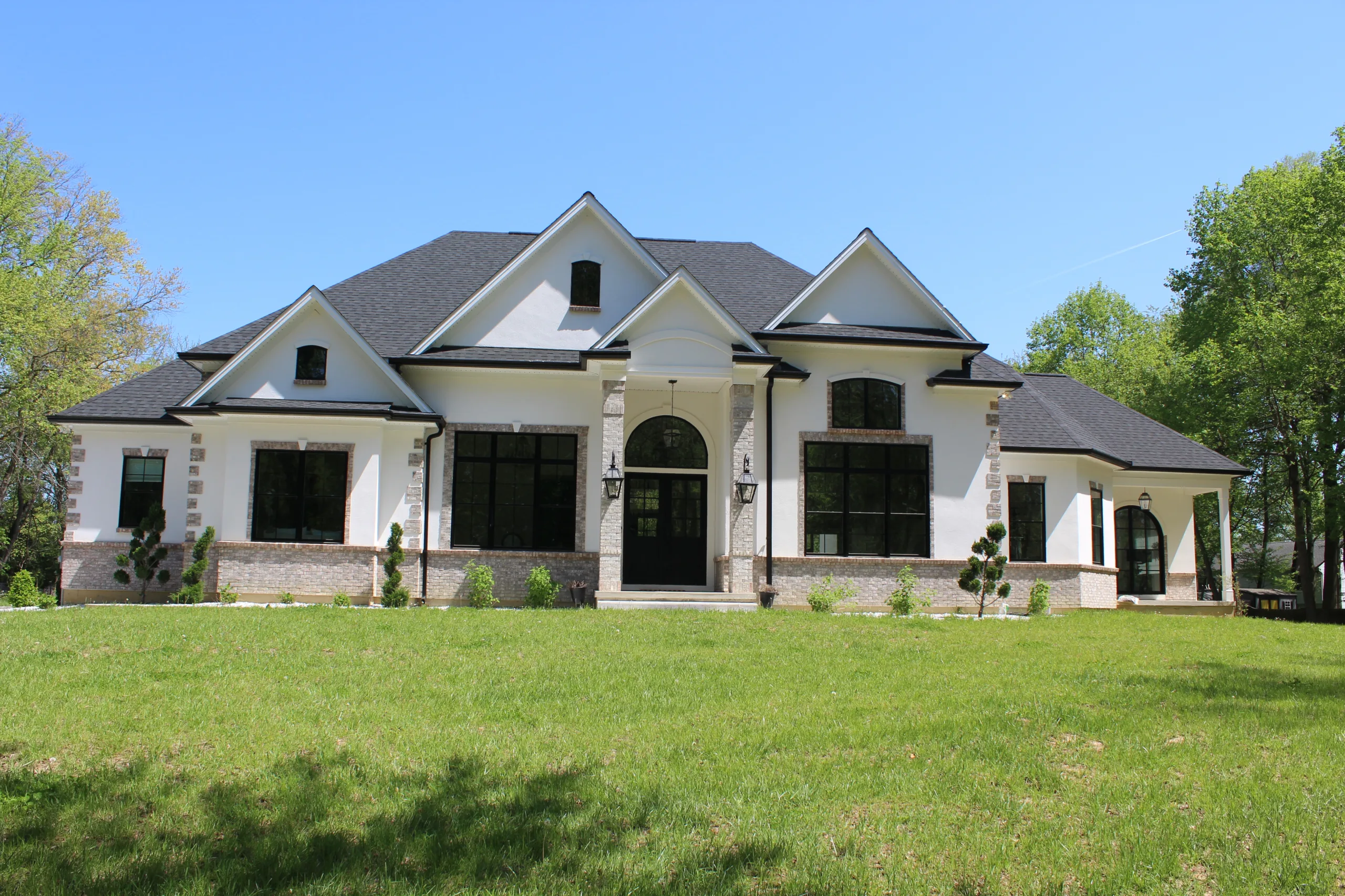A white and black house with a green lawn.